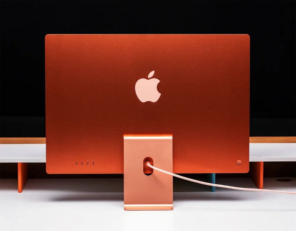 An orange desktop Mac on a white shelf